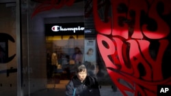 A cleaner wipes window panels near a shop of American sportswear brand Champion, at the capital city's popular shopping mall in Beijing, Feb. 13, 2019.