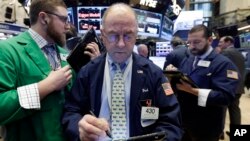 Frederick Reimer, center, works with fellow traders on the floor of the New York Stock Exchange, Jan. 27, 2017.