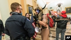 FILE - Supporters of President Donald Trump are confronted by U.S. Capitol Police officers outside the Senate Chamber inside the Capitol in Washington, Jan. 6, 2021. The Arizona man seen in the fur hat, Jacob Chansley, was taken into custody Jan. 9.