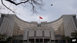 FILE - The national flag flies in front of China's central bank in Beijing, Jan. 20, 2022. Ratings agency Moody's cut its outlook on China's government credit ratings to negative from stable, Dec. 5, 2023.