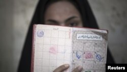 A woman holds her identification in front of her face after voting at a polling station during Iran's parliamentary election in southern Tehran, March 2, 2012.