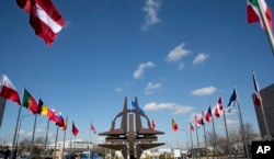 FILE - NATO symbol and flags of the NATO nations outside NATO headquarters in Brussels.