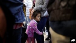 FILE - Nicole Hernandez, of the Mexican state of Guerrero, holds on to her mother as they wait with other families to request political asylum in the United States, across the border in Tijuana, Mexico, June 13, 2018.