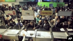 With Moscow's Domodedovo Airport temporarily shut down due to icy rain passengers queue in front of ticket and information counters Sunday, 26 Dec 2010