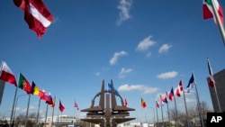 FILE - NATO symbol and flags of the NATO nations outside NATO headquarters in Brussels. 
