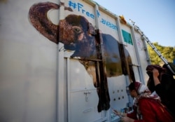 Volunteers paint an image of an elephant named "Kaavan" on a crate to be used to be transported Kaavan to a sanctuary in Cambodia, at the Maragzar Zoo in Islamabad, Pakistan, Nov. 27, 2020.