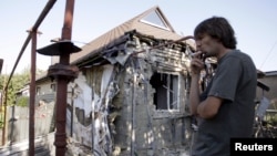 FILE - A man smokes near a residential building, which locals said was damaged during recent shelling, in Donetsk, Ukraine, Aug. 7, 2015. 