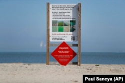 A warning sign against algae bloomsstands on an empty Maumee Bay State Park public beach on Lake Erie in Oregon, Ohio, on Friday, September. 15, 2017.