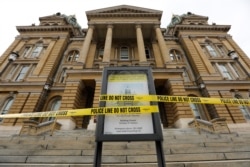 Police tape is wrapped around a sign in front of a closed entrance at the Statehouse in Des Moines, Iowa, March 16, 2020. Iowa leaders are suspending the legislative session for at least 30 days because of the coronavirus.