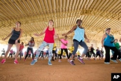 FILE - Fitness enthusiasts run through dance exercises as they work out at Tropical Park in Miami, Florida.