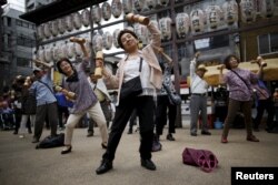 Elderly and middle-age people exercise with wooden weights during a health event to celebrate Japan's "Respect for the Aged Day" at a temple in Tokyo, 2015.
