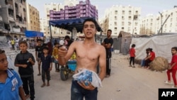 Palestinians collect food items from airdropped aid parcels in the Hamad City area in Khan Yunis in the southern Gaza Strip on July 4, 2024.