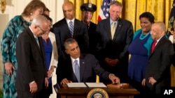 Surrounded by LGBT supporters, President Barack Obama signs executive orders to protect LGBT employees from federal workplace discrimination, in the East Room of the White House in Washington, July 21, 2014.
