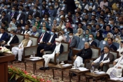Afghan President Ashraf Ghani, center, wearing a protective face mask to help curb the spread of the coronavirus attends an Afghan Loya Jirga meeting in Kabul, Afghanistan, Aug. 7, 2020.