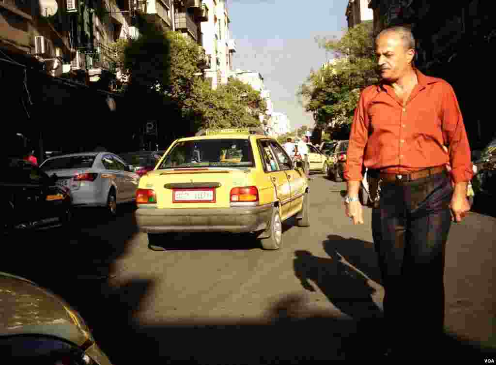 A man crosses a busy street in Damascus. Though some streets are closed to traffic due to safety concerns, most of the roads remain open. (J. Weeks/VOA)