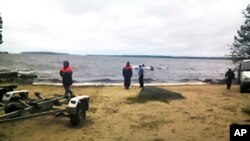 In this Russian Emergency Situations Ministry photo, made available on Sunday, June 19, 2016, Russian Ministry for Emergency Situations workers stand at the site of an incident, at a lake in Russia's northwestern region of Karelia, Russia.