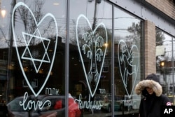 A woman walks past the window of a Starbucks in the Squirrel Hill neighborhood of Pittsburgh, Nov. 20, 2018. In the wake of the Tree of Life massacre, Squirrel Hill residents aren't shying away from celebrating Thanksgiving. They’re welcoming it.