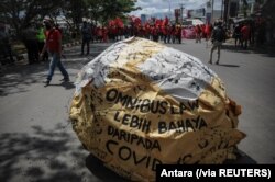 Tulisan &quot;omnibus law lebih berbahaya dari COVID&quot; tampak di tengah demo buruh memprotes Undang-Undang Cipta Kerja, di Bandung, Jawa Barat, Selasa, 6 Oktober 2020. (Foto: Antara via Reuters)