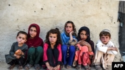 FILE - Children sit in front of a house at Deh Qubad village in Maiwand district of Kandahar province, Afghanistan, Sept. 27, 2020. 