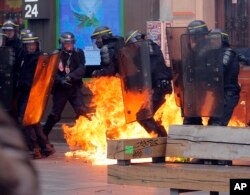 Leftist protesters throw a petrol bomb at riot policemen during clashes in Paris, France, Sept. 15, 2016.