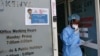 FILE -Llaboratory technician Irene Ooko walks outside to take a nasal sample from a patient seeking a test for the new coronavirus that causes COVID-19, at the Pathologists Lancet Kenya laboratory in Nairobi, Kenya.