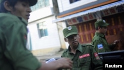 FILE - Soldiers from the United Wa State Army ride in a vehicle on a street in Namteuk, neighboring China's border town of Mangka, Myanmar.