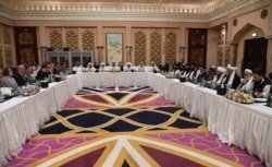 FILE - A handout photo released by the official Qatar's Ministry of Foreign Affairs on Feb. 26, 2019, shows Qatari officials, center, taking part in meeting between the U.S. delegation, left, and the Taliban delegation in Doha.