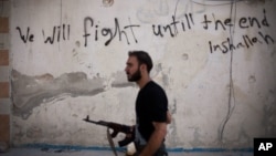 FILE - Free Syrian Army fighter walks through a street in the Amariya district in Aleppo, Syria. 