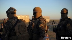 FILE - Fighters of Syrian Democratic Forces (SDF) are seen standing near the village of Baghuz, Deir al-Zour province, Syria, March 1, 2019.