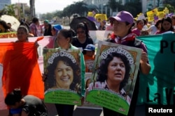 Activists hold pictures of slain environmental rights activist Berta Caceres during a protest to mark International Women's Day outside the presidential house in Tegucigalpa, Honduras, March 8, 2016.