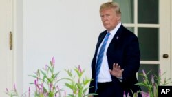 President Donald Trump waves to members of the media as he walks toward the West Wing of the White House in Washington, July 18, 2018.
