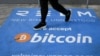 Un homme passe devant une bannière avec le logo du bitcoin pendant la conférence sur les crypto-monnaies Bitcoin 2021 Convention au Mana Convention Center à Miami, en Floride, le 4 juin 2021.