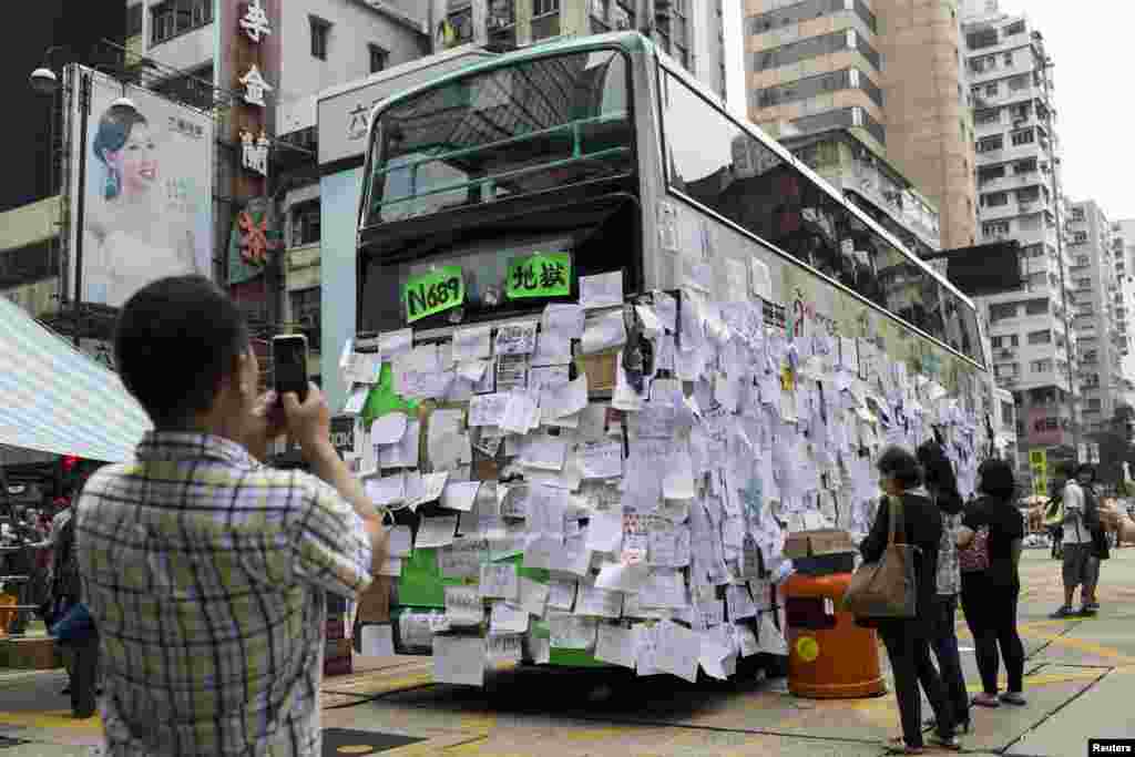 A man takes a picture of a bus covered with messages of support at Mongkok shopping district after thousands of protesters blocked the road in Hong Kong, Sept. 30, 2014. 
