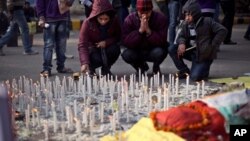 Satu keluarga India menyalakan lilin untuk mengenang perempuan korban perkosaan beramai-ramai di New Delhi bulan lalu, hari Sabtu (5/1).