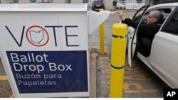 FILE - A voter drops off his election ballot in the drop box at the Cuyahoga County Board of Elections, in Cleveland, Ohio, April 22, 2020.