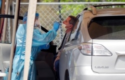 A medical worker tests a person for the coronavirus at a drive-through facility primarily for first responders and medical personnel in San Antonio, March 17, 2020.