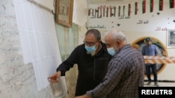Des électeurs vérifient leur nom pour recevoir leur carte d'électeur dans un bureau de vote à Tripoli, en Libye, le 8 novembre 2021.