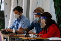 Examiners wear face shields and masks to prevent the spread of COVID-19, during end of year secondary school exams at high school Liceo Kennedy, in Rome, June 17, 2020.