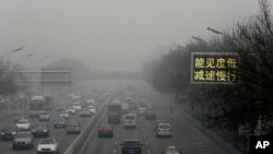 Vehicles drive along a road with a traffic sign reading "Visibility low, slowdown the speed" on a heavily polluted day in Beijing, Monday, Nov. 30, 2015.