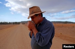 Farmer Ash Whitney lights a cigarette as he stands in the middle of a road that divides his drought-affected property, located west of the town of Gunnedah, in northwestern New South Wales in Australia, June 3, 2018.
