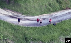 This photo made available by the U.S. Coast Guard shows residents near Utado Puerto Rico, waiting for supplies to be dropped from the air, Oct. 3, 2017.