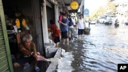 A man discards water from his house as water overflows from the Chao Phraya river to the street at Phranakhon district in Bangkok, October 24, 2011