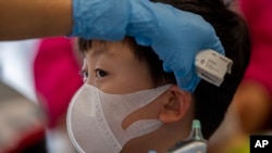 A health worker checks the temperature of tourist from Wuhan, China, as he waits for a charter flight back to Wuhan at the Suvarnabhumi airport, Bangkok, Thailand, Jan. 31, 2020.