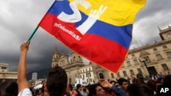 FILE - A supporter of the peace deal between the Colombian government and rebels of the Revolutionary Armed Forces of Colombia waves a flag during a rally in front of Congress, in Bogota, Colombia, Oct. 3, 2016.