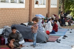 FILE - Internally displaced Afghan families, who fled from the northern province due to battle between Taliban and Afghan security forces, sit in the courtyard of the Wazir Akbar Khan mosque in Kabul, Aug. 13, 2021.