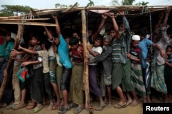 Rohingya refugees jostle as they line up for a blanket distribution under heavy rainfall at the Balukhali camp near Cox's Bazar, Bangladesh, Dec. 11, 2017.