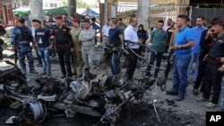 Iraqi security forces and civilians inspect the site of a deadly car bomb explosion, in Baghdad, Iraq, May 30, 2017.