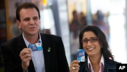 Nawal El Moutawakel, head of the IOC Evaluation Commission, right, and Eduardo Paes, Rio de Janeiro's Mayor, show tickets before boarding a Bus Rapid Transit (BRT) during the 3rd visit of the IOC Coordination Commission for the Rio Olympics 2016 in Rio de