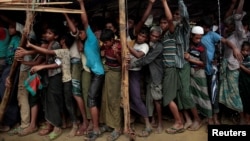Rohingya refugees jostle as they line up for a blanket distribution under heavy rainfall at the Balukhali camp near Cox's Bazar, Bangladesh, Dec. 11, 2017.