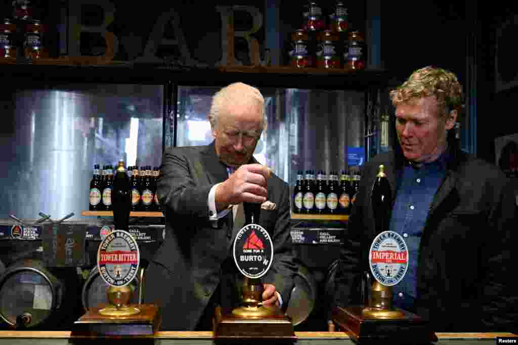 Britain's King Charles pulls a pint alongside Tower Brewery owner John Mills, during a visit to the Tower Brewery in Burton-Upon-Trent.